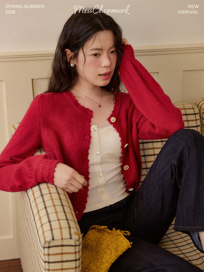 Model wearing a red knit cardigan over a cream top