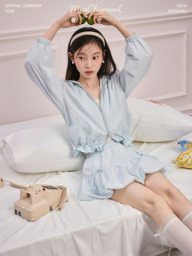 Model wearing a light blue matching lounge set with zip-up top and shorts