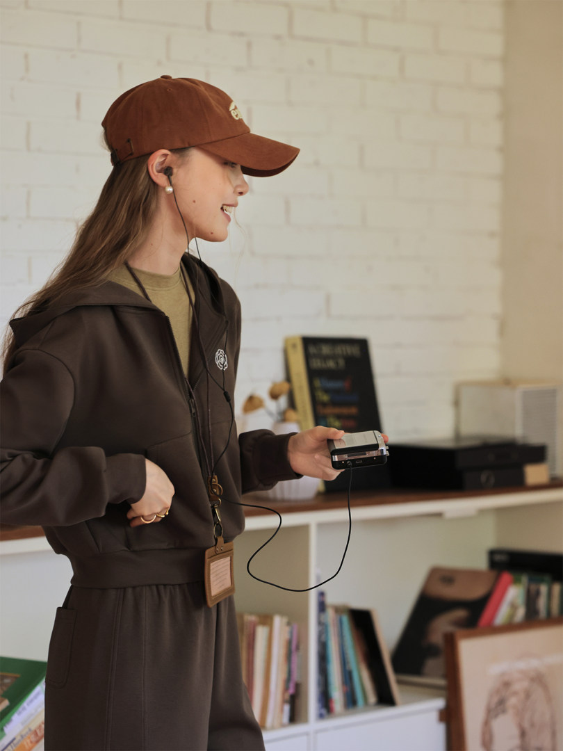 Woman wearing a dark brown hoodie and matching pants with a brown cap