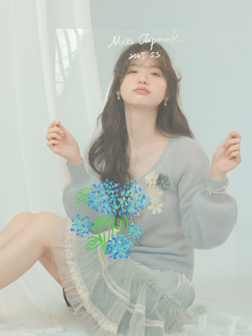 Model wearing a light blue knit sweater and sheer ruffled skirt