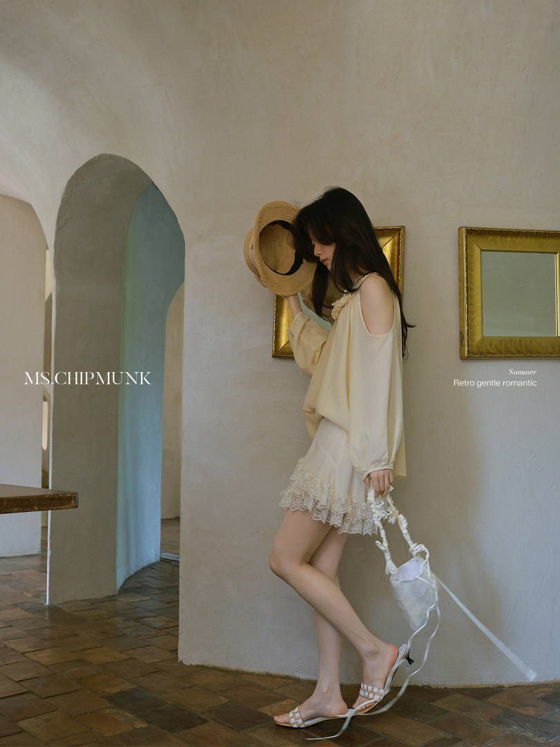Model wearing a cream summer outfit with a wide-brim hat and lace-trim shorts
