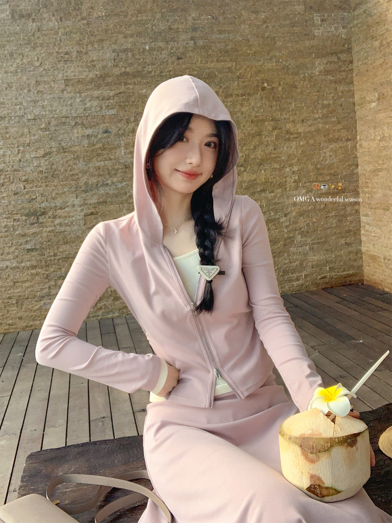 Woman wearing a light pink hooded zip-up jacket and matching skirt set