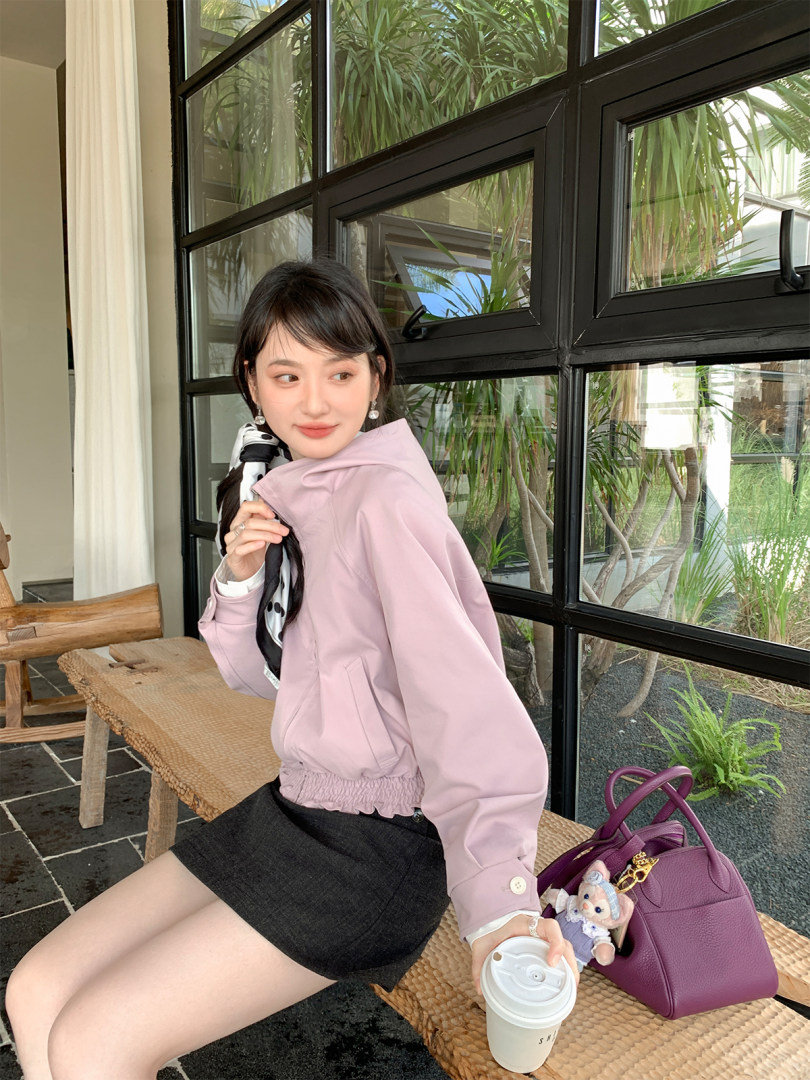 Model wearing a light pink cropped jacket with a black mini skirt