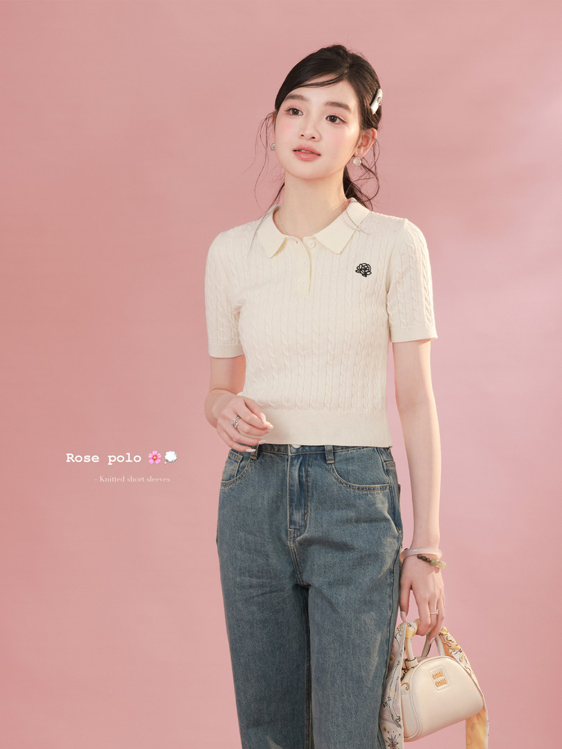 Model wearing a cream short-sleeve knitted polo top with jeans on a pink background