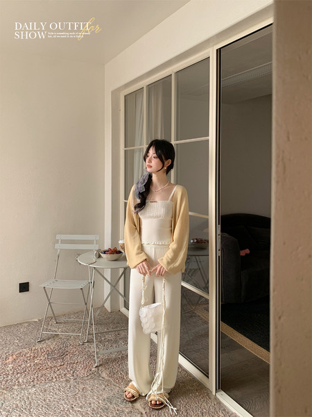 Model wearing a light cream cardigan and matching outfit indoors