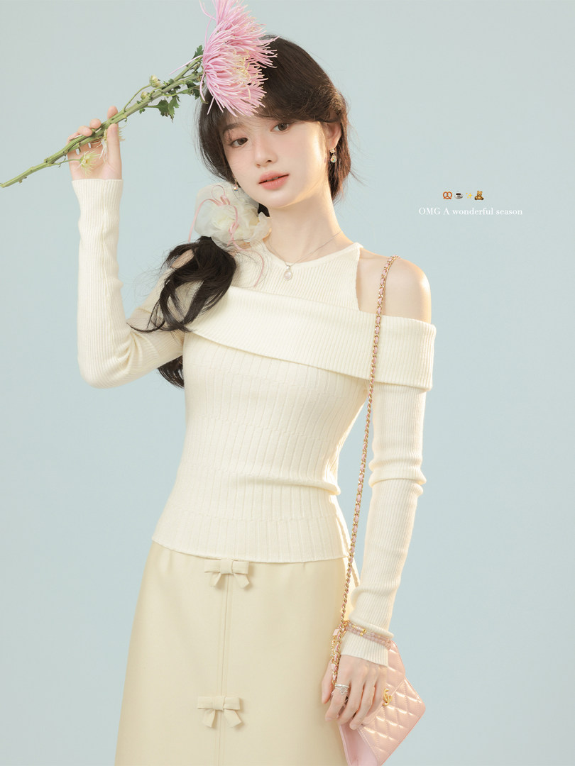 Model wearing a cream off-shoulder ribbed knit top with a beige skirt and pink quilted handbag