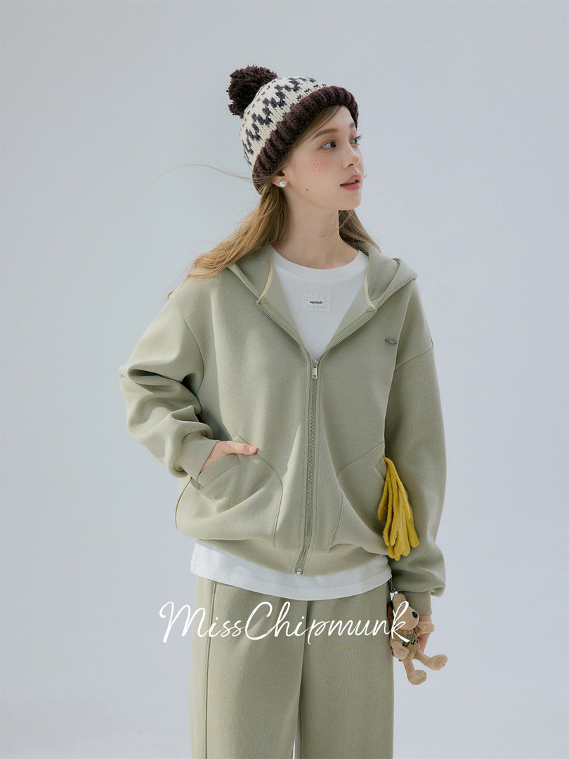 Model wearing a light green zip-up hoodie and matching pants with a knit beanie