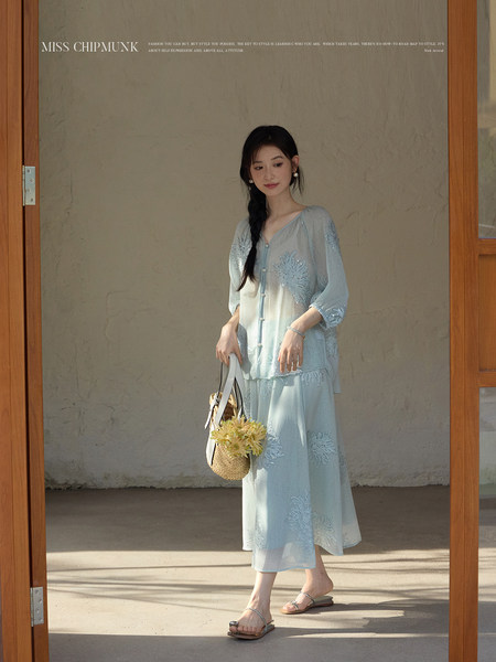 Model wearing a light blue embroidered two-piece outfit with sandals