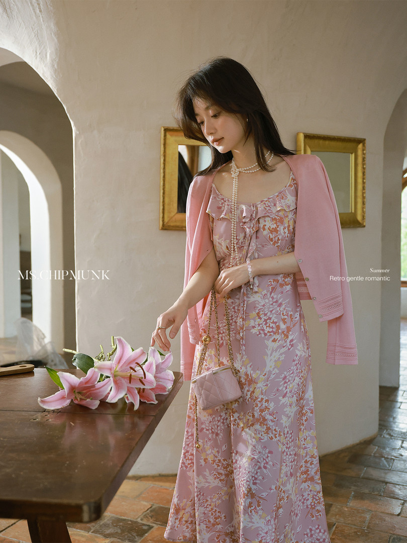 Woman wearing a pink floral dress with a matching cardigan and small quilted bag