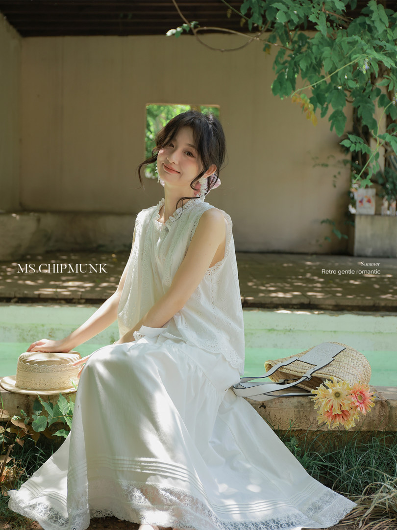 Woman wearing a white lace sleeveless dress in an outdoor summer scene