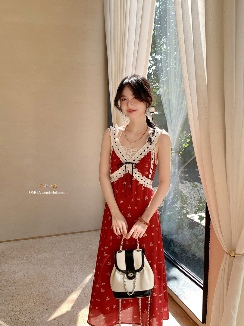 Model wearing a red floral sleeveless dress with lace trim and a small handbag