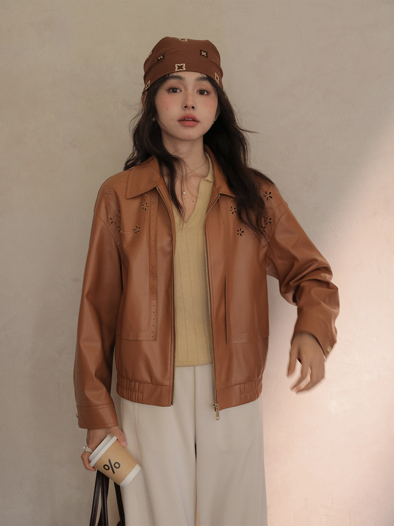 Woman wearing a brown faux leather jacket with a bandana headscarf and light pants
