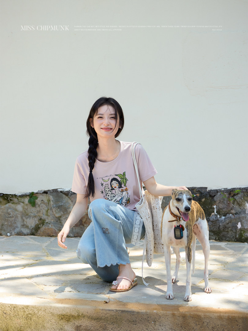 Model wearing a pink graphic T-shirt with light blue jeans outdoors
