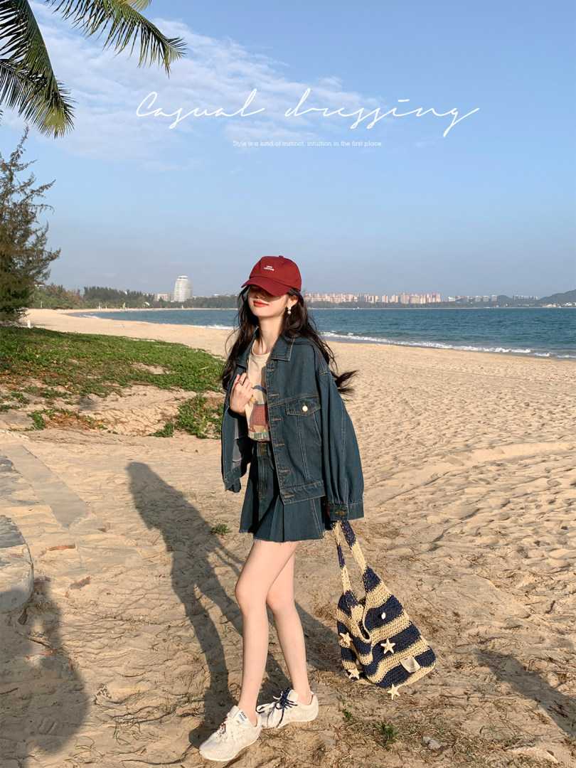 Woman wearing a denim outfit with cap and sneakers on a beach