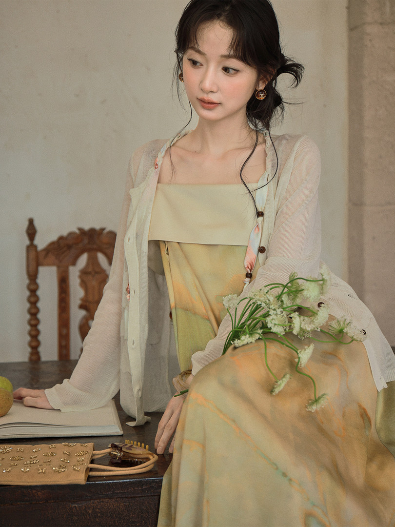 Woman wearing a light pastel dress with a sheer cardigan