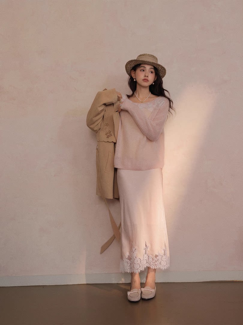 Model wearing a pastel pink dress with a straw hat and beige jacket