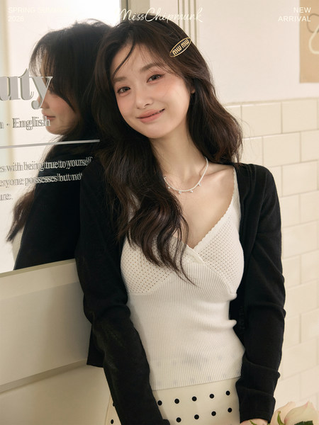 Woman wearing a white knit camisole with a black cardigan