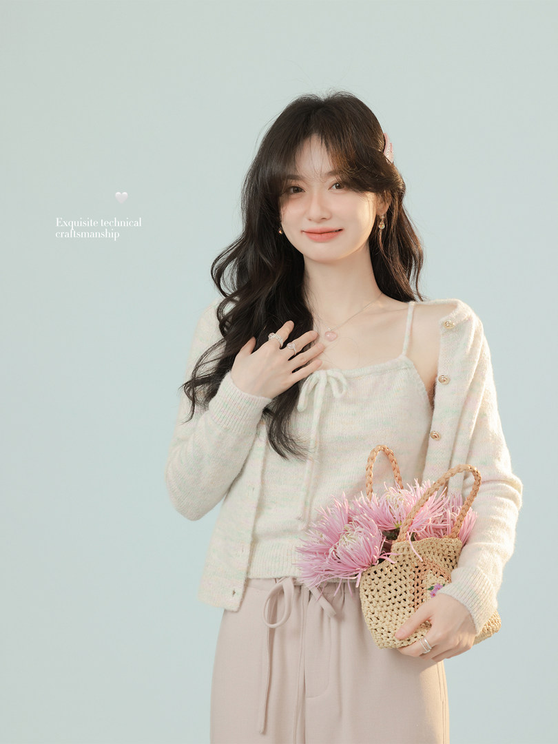 Woman wearing a cream knit cardigan and matching top, holding a woven handbag