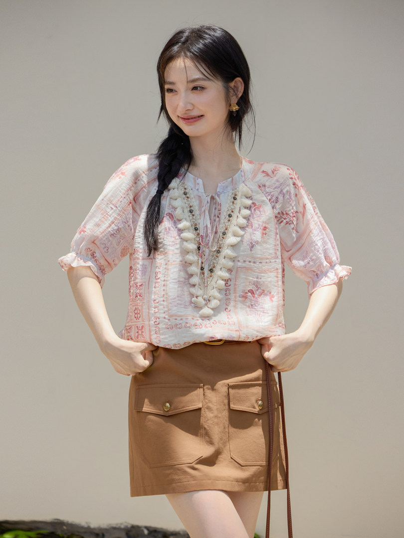 Woman modeling a light pink patterned blouse with puff sleeves and a brown skirt