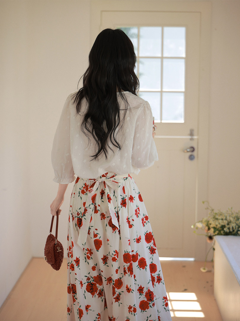 Woman wearing a white blouse with a red floral skirt indoors