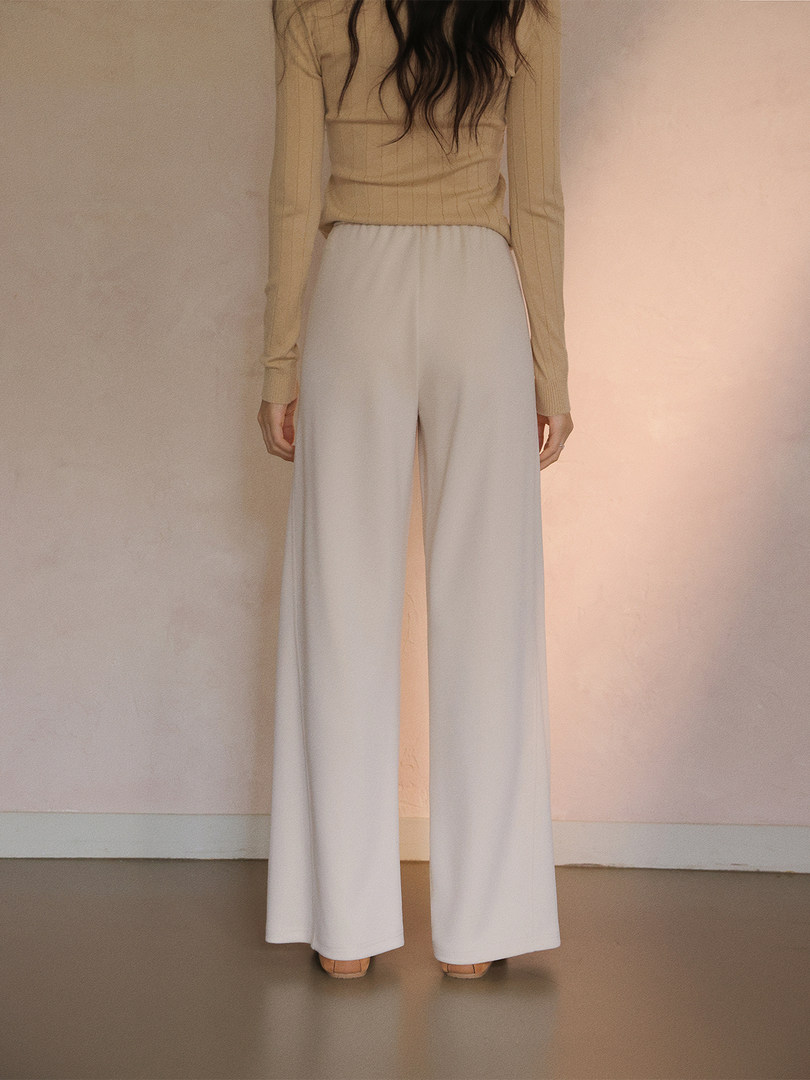 Model wearing cream wide-leg pants with a beige ribbed top