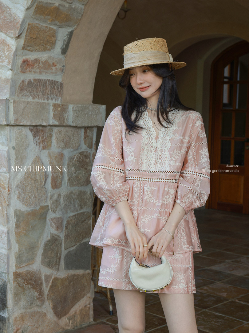 Model wearing a pink embroidered summer dress with a straw hat and small handbag