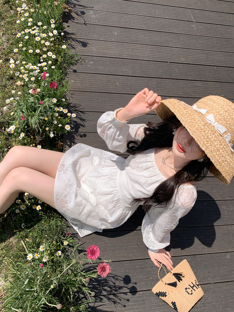 Woman wearing a white lace dress and straw hat with a woven bag outdoors