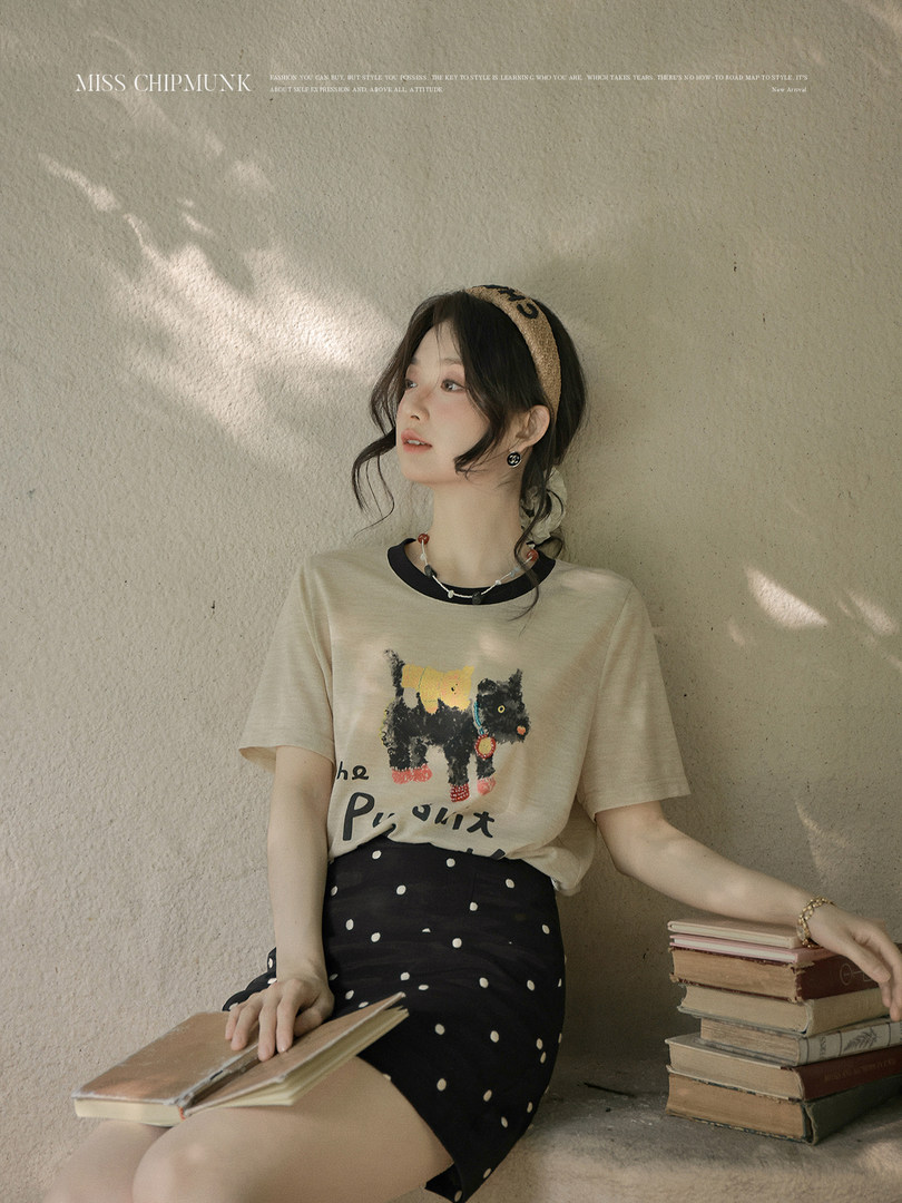 Model wearing a beige graphic T-shirt with a black polka dot skirt