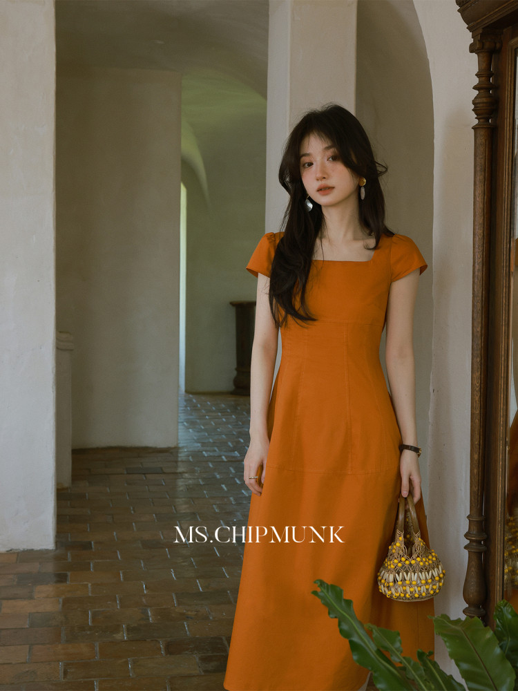 Woman wearing an orange square-neck midi dress indoors
