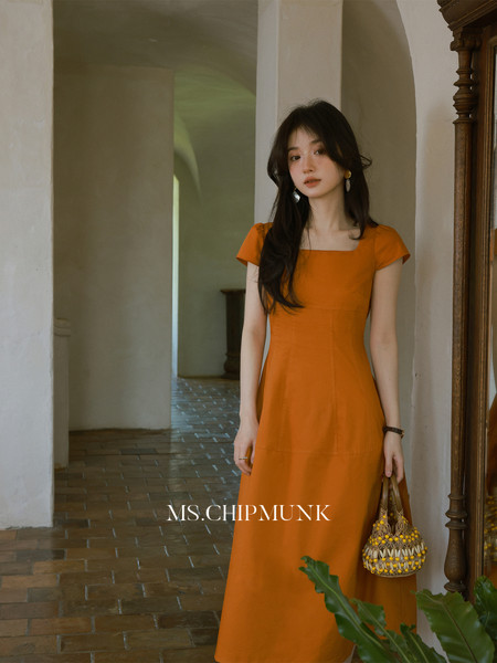 Woman wearing an orange square-neck midi dress indoors