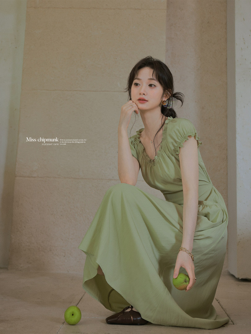 Woman wearing a light green flowy dress on a neutral background