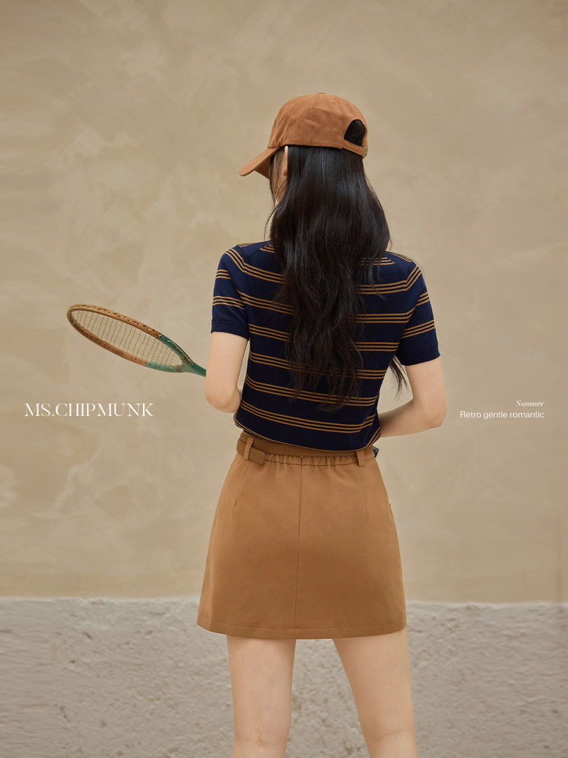 Model wearing a striped short-sleeve top with a brown skirt and cap