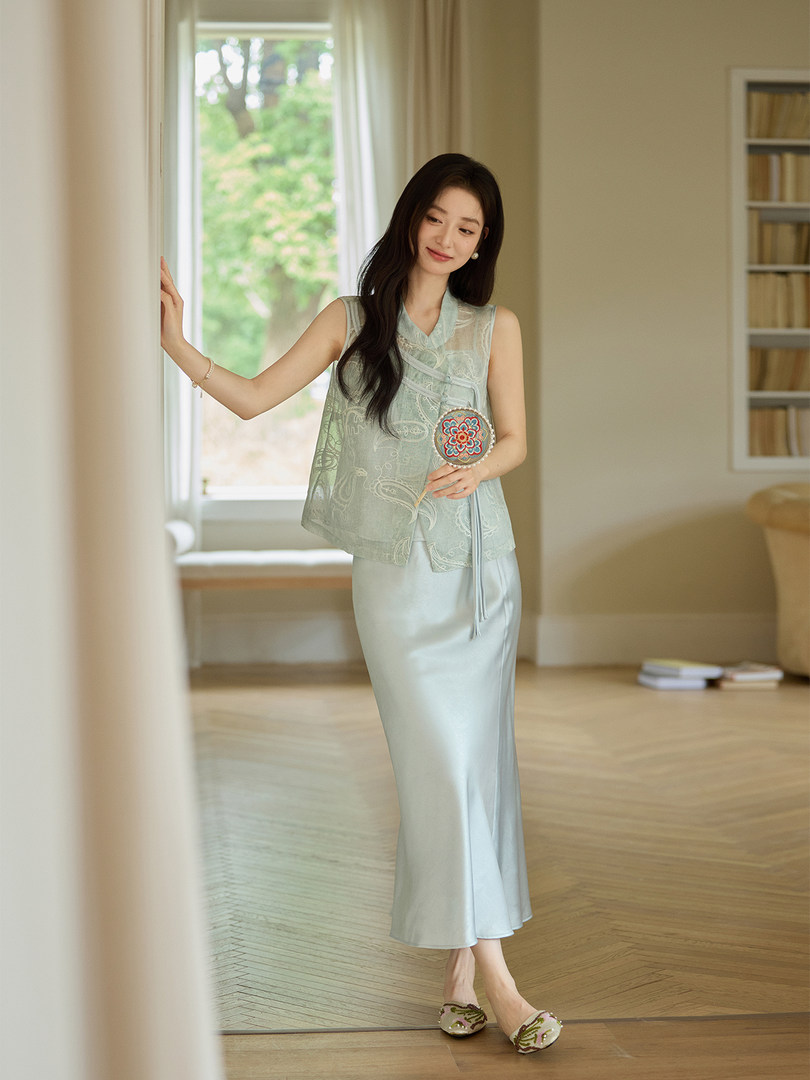 Woman wearing a light mint sleeveless top and long skirt indoors