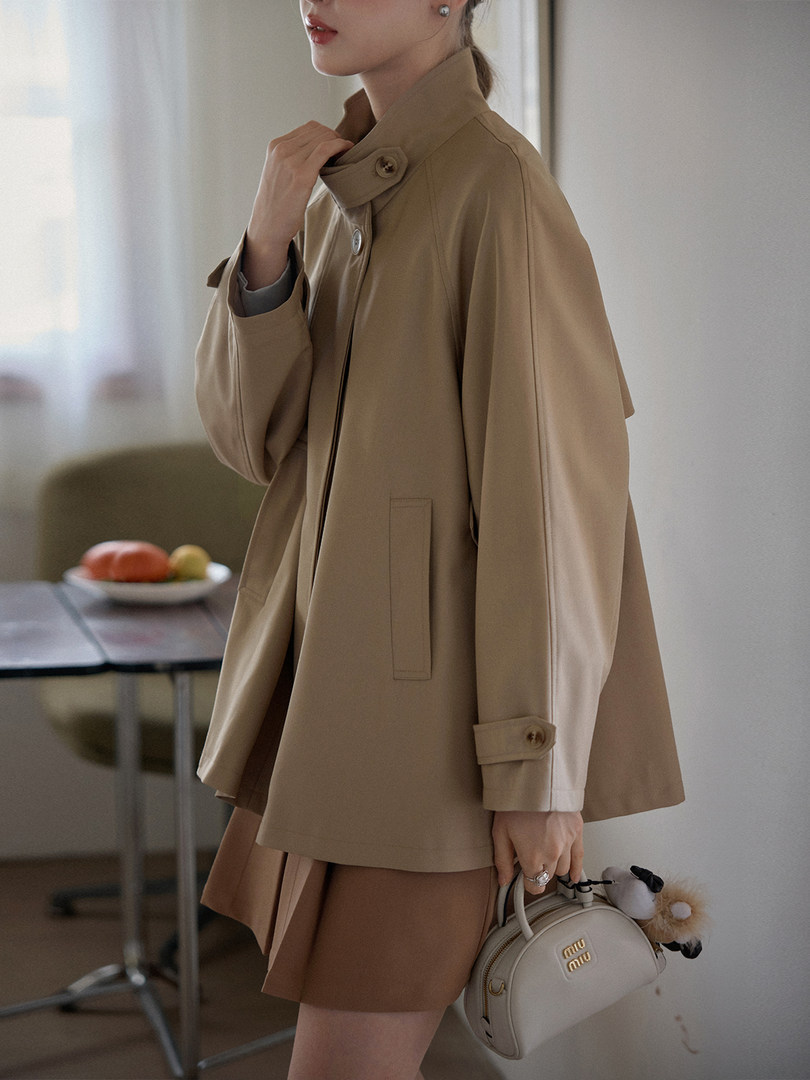 Beige trench-style coat worn by a model with a small handbag