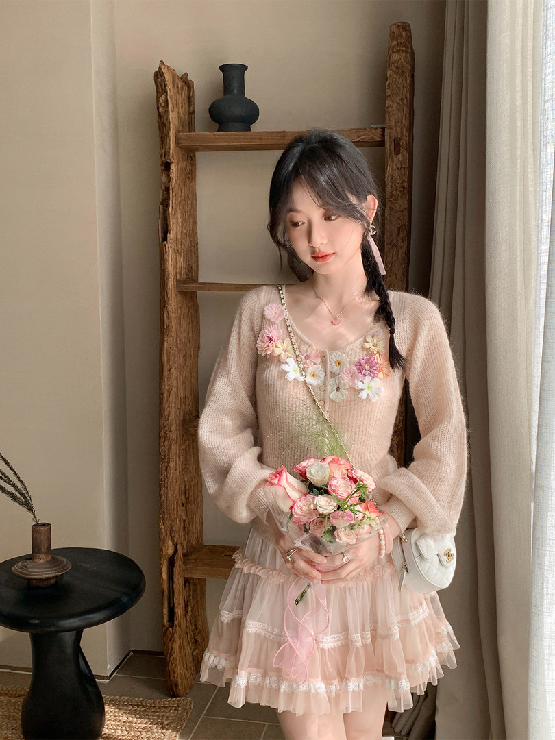 Woman wearing a pastel floral knit top with a pink ruffled skirt and small shoulder bag