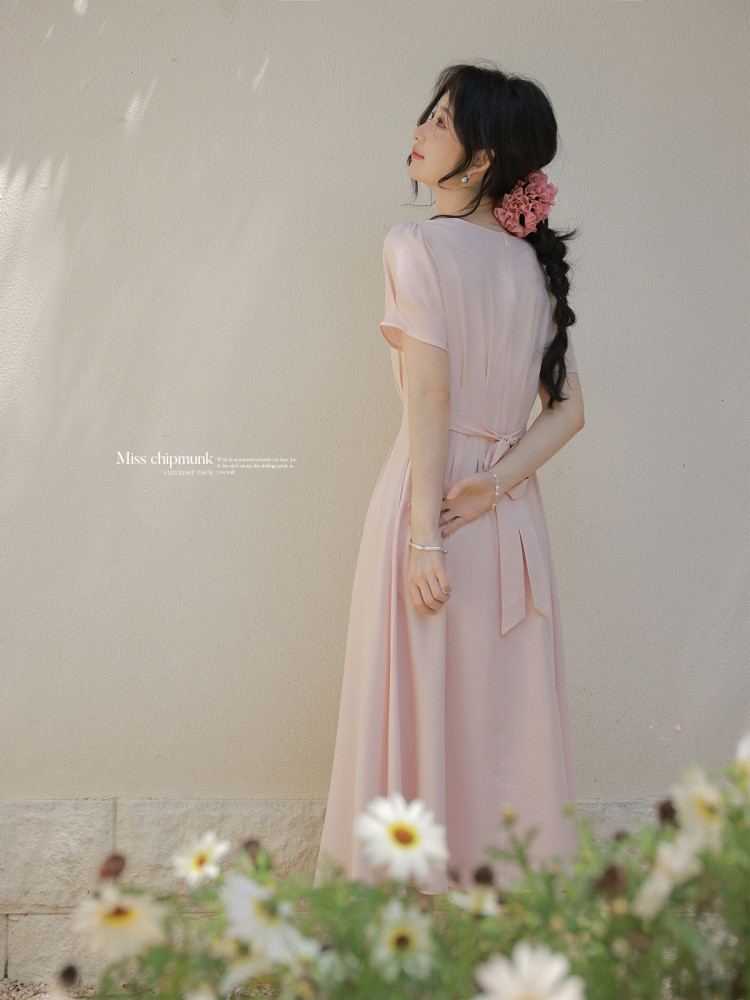 Woman wearing a light pink flowing dress with a tied waist