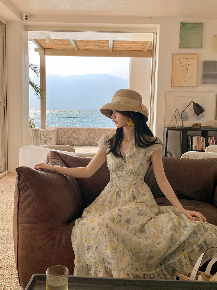 Woman wearing a floral dress and wide-brim hat in a seaside living room