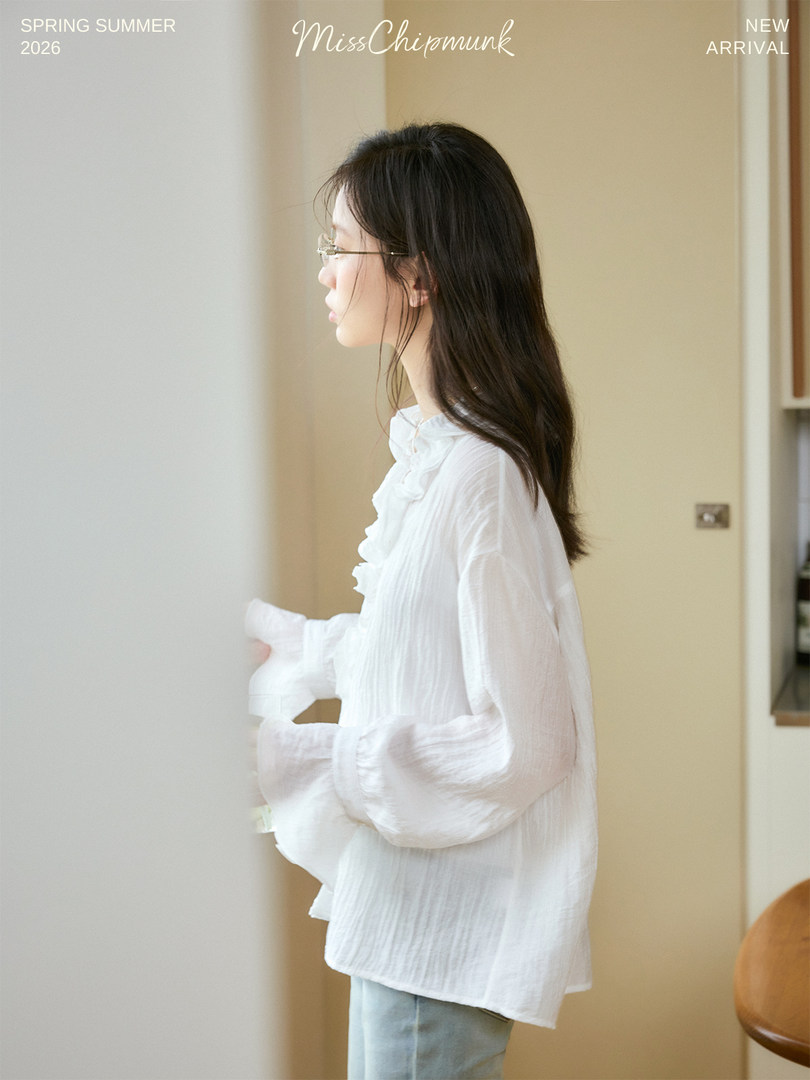 Woman wearing a white lightweight blouse with ruffled details