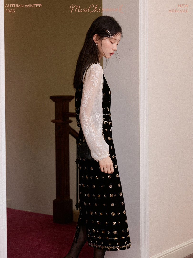 Female model wearing a black embellished dress with sheer white sleeves