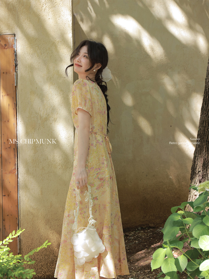 Model wearing a light yellow floral midi dress outdoors