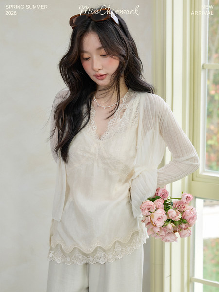 Model wearing a cream lace blouse and matching sheer top with delicate floral details