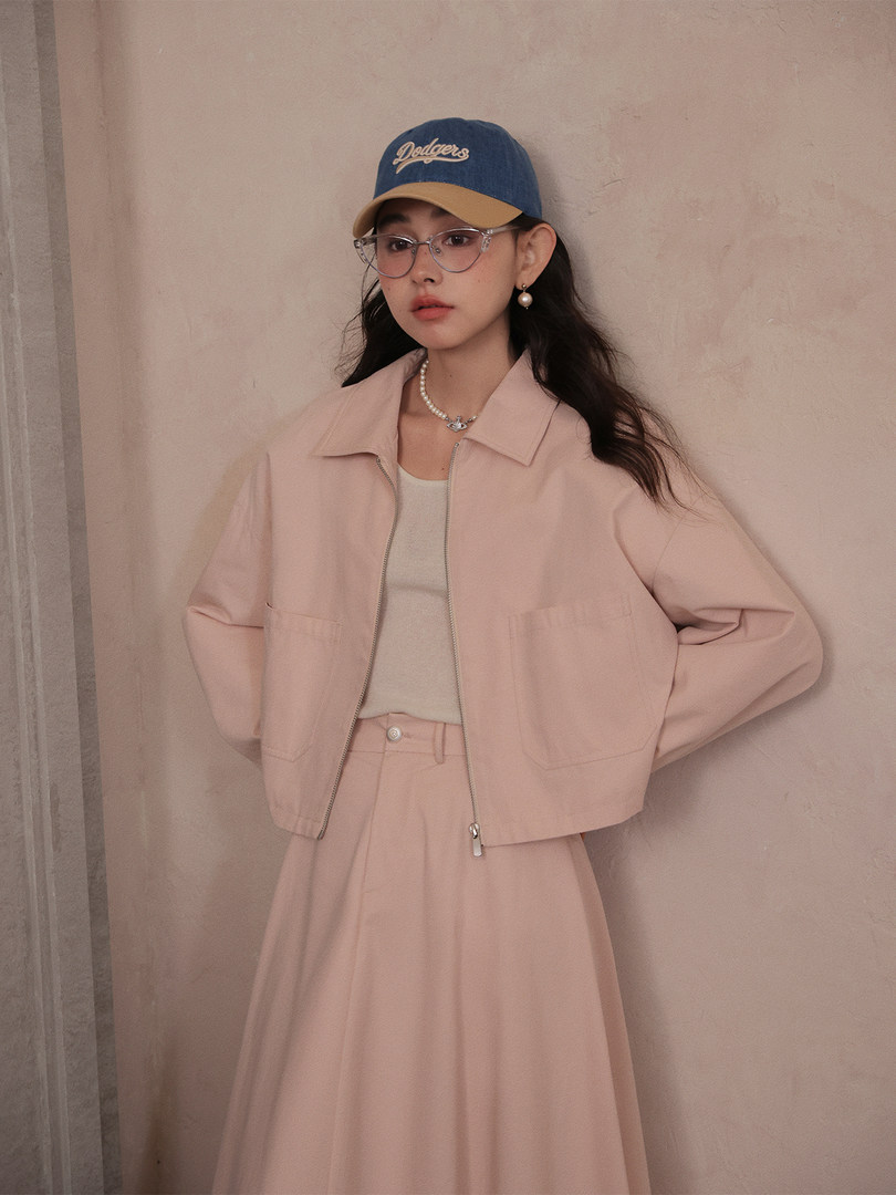 Woman wearing a pink jacket and matching skirt with a blue baseball cap