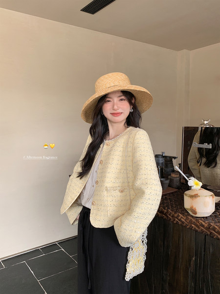 Woman wearing a pale yellow textured jacket and straw hat