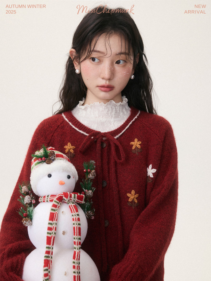 Model wearing a red fuzzy cardigan with floral details and a snowman accessory