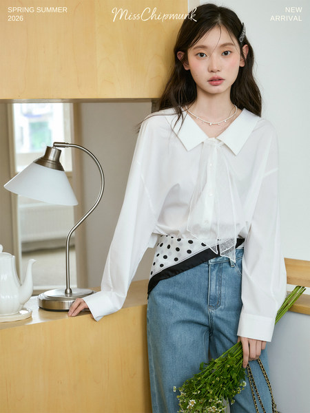 Model wearing a white long-sleeve blouse with a collar, layered over jeans in a spring-summer fashion shoot