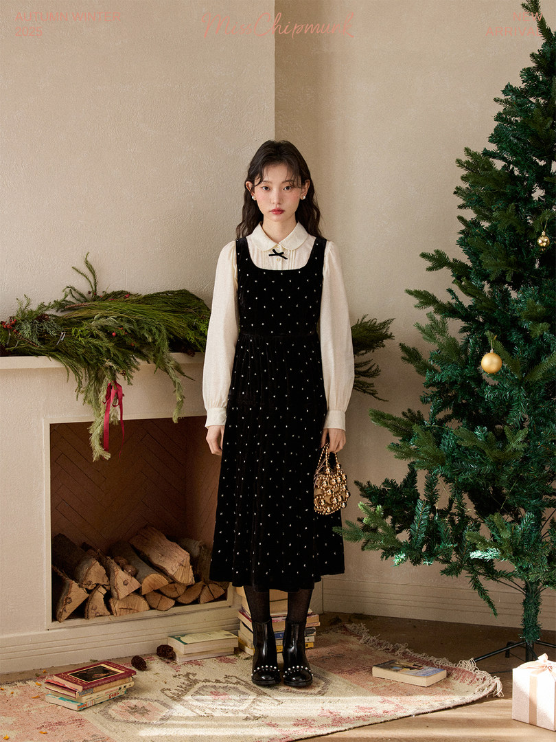 Model wearing a black midi dress layered over a white blouse in a festive winter setting