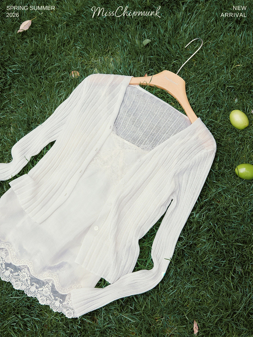 White lightweight knit cardigan and dress laid on grass on a hanger