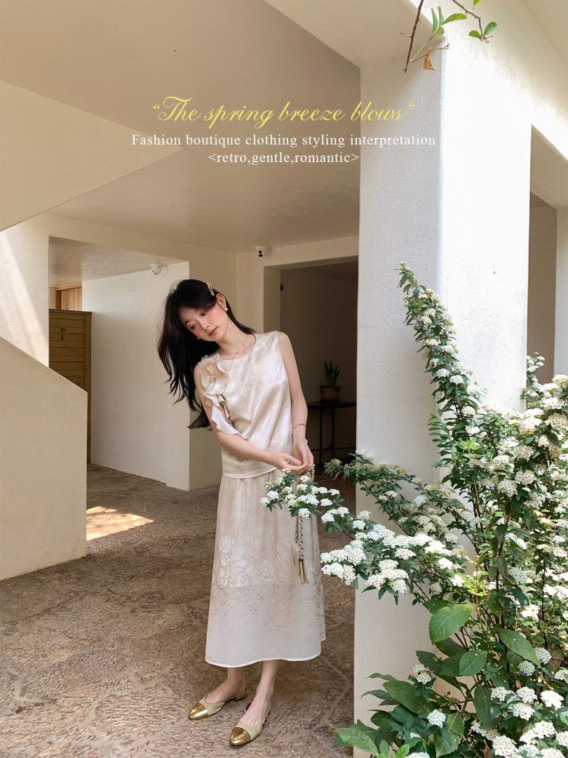 Woman wearing a light cream sleeveless midi dress in a bright courtyard setting