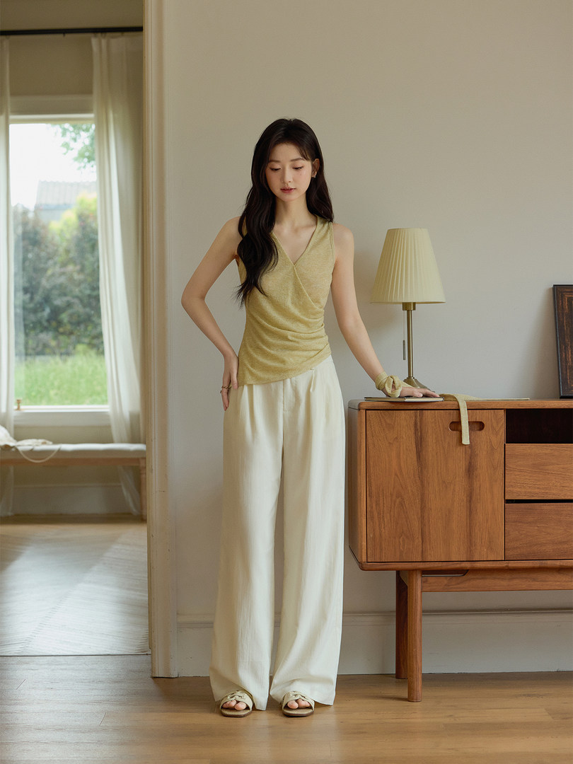 Woman modeling a yellow sleeveless top with white wide-leg pants and sandals indoors