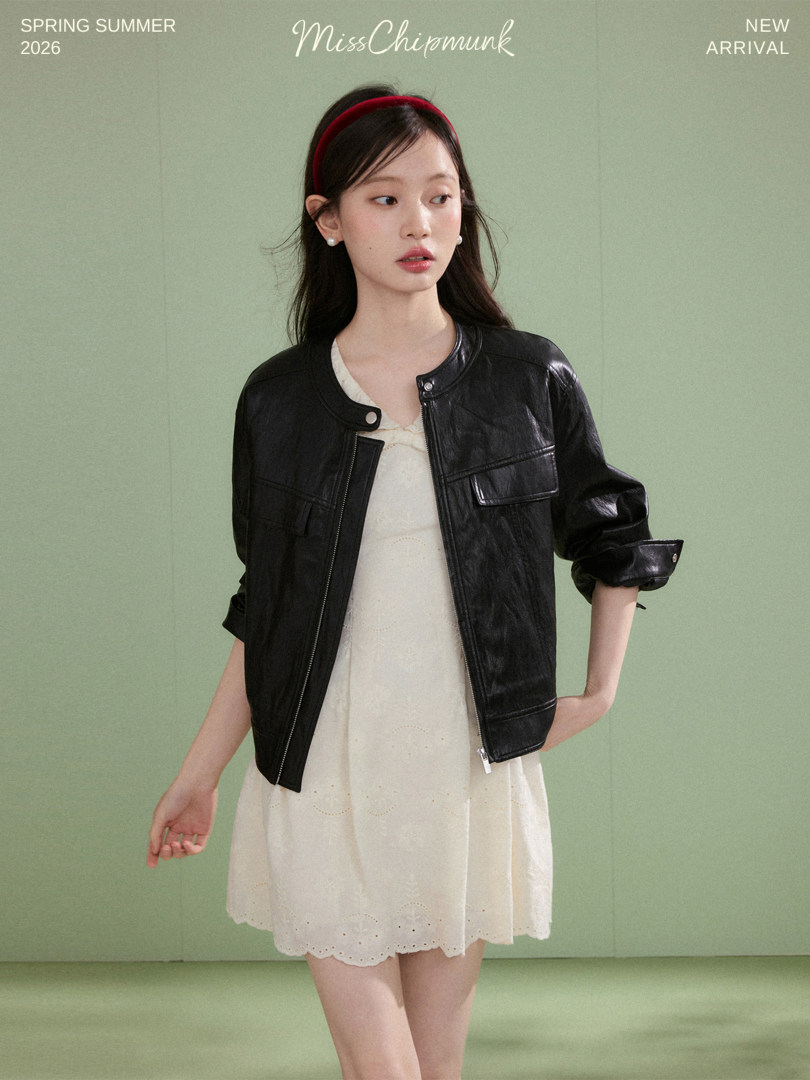 Model wearing a black leather jacket over a cream dress